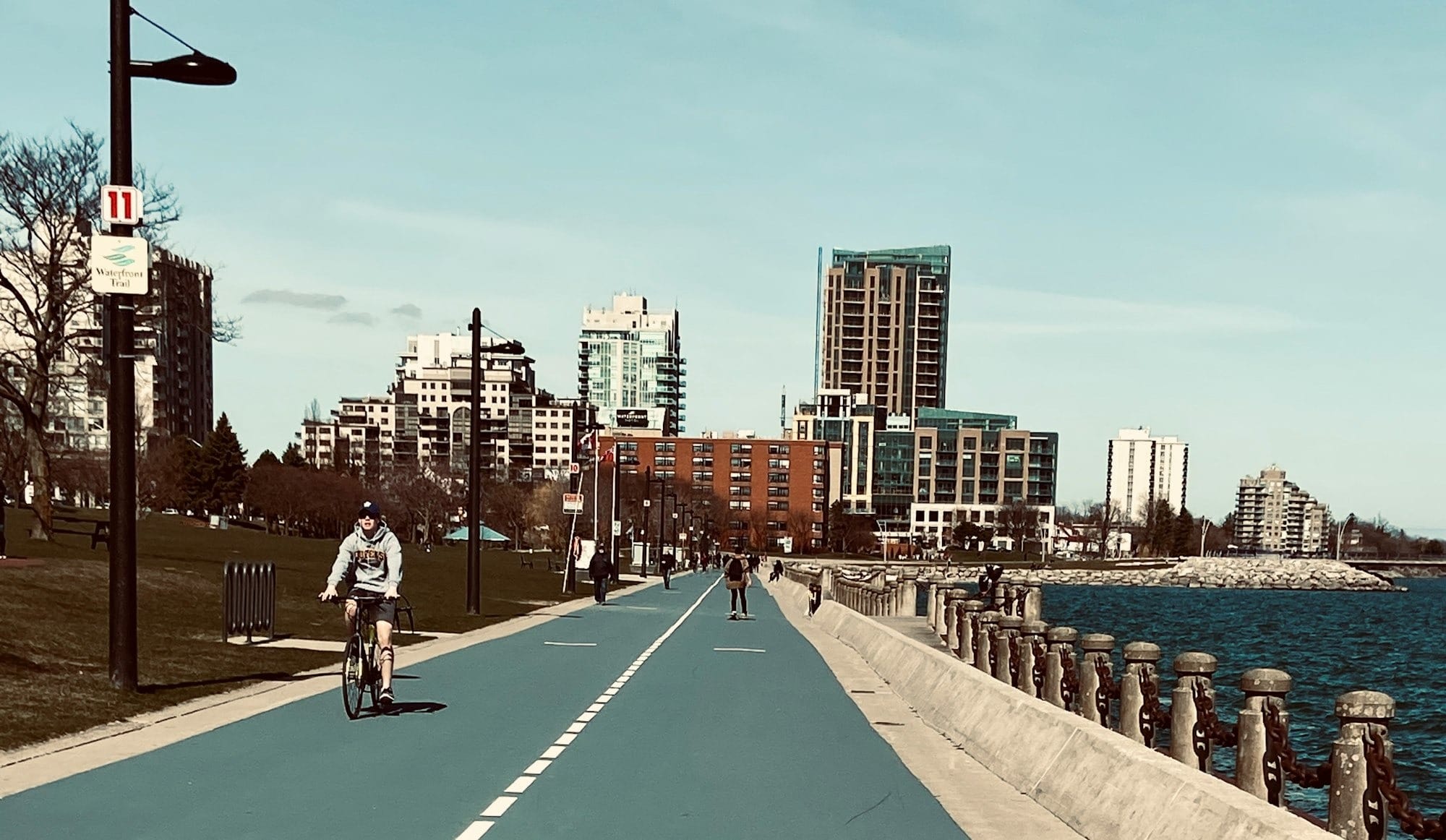 people walking on sidewalk near body of water during daytime