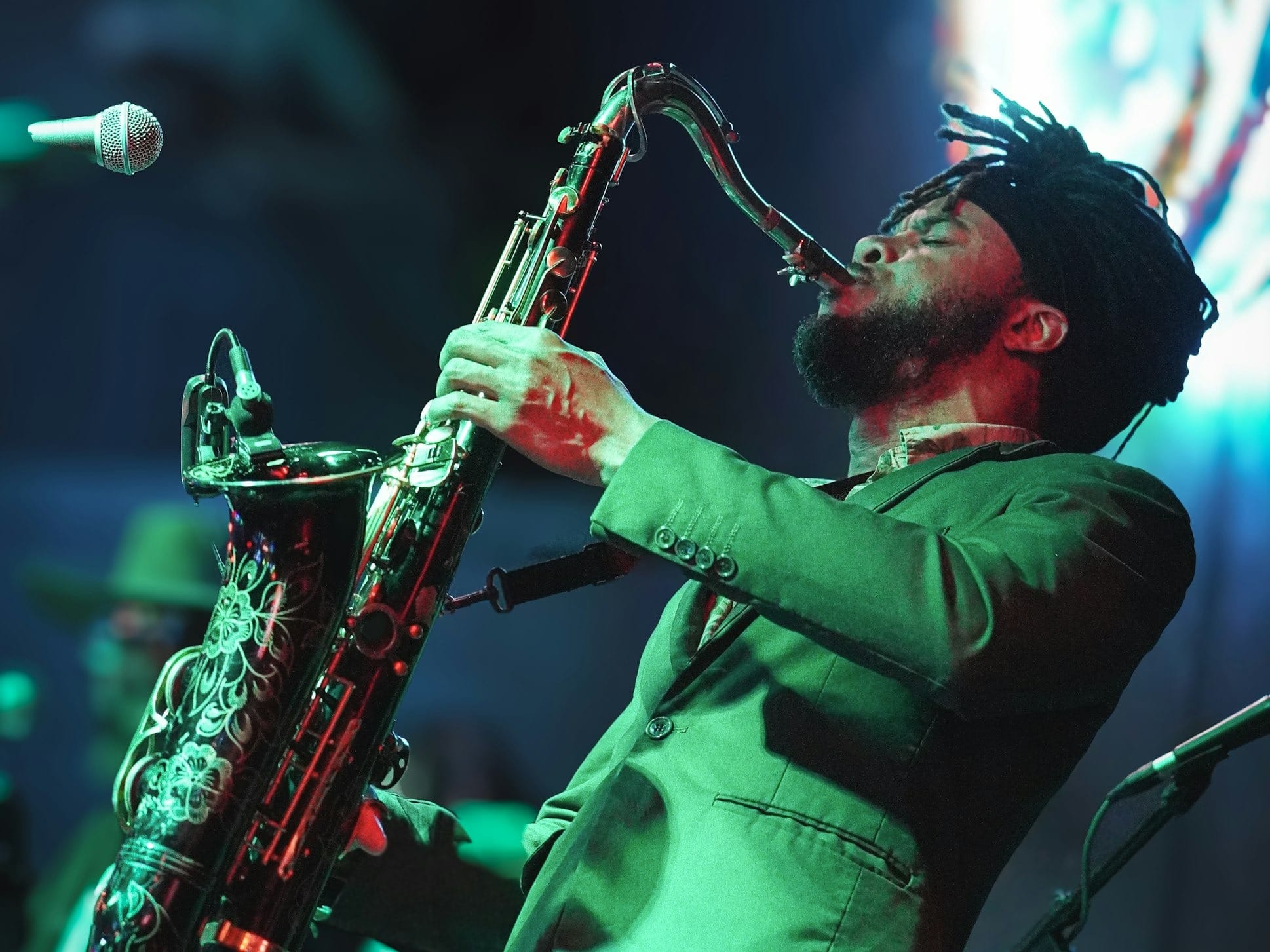 a man in a green suit playing a saxophone